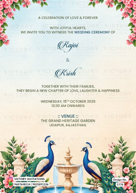 A wedding invitation card featuring a light blue and cream gradient background with pink floral borders at the top, elegant black and blue text in the center, and two peacocks standing beside a fountain at the bottom. The brand name 'Victory Invitations' is visible in the bottom left corner.